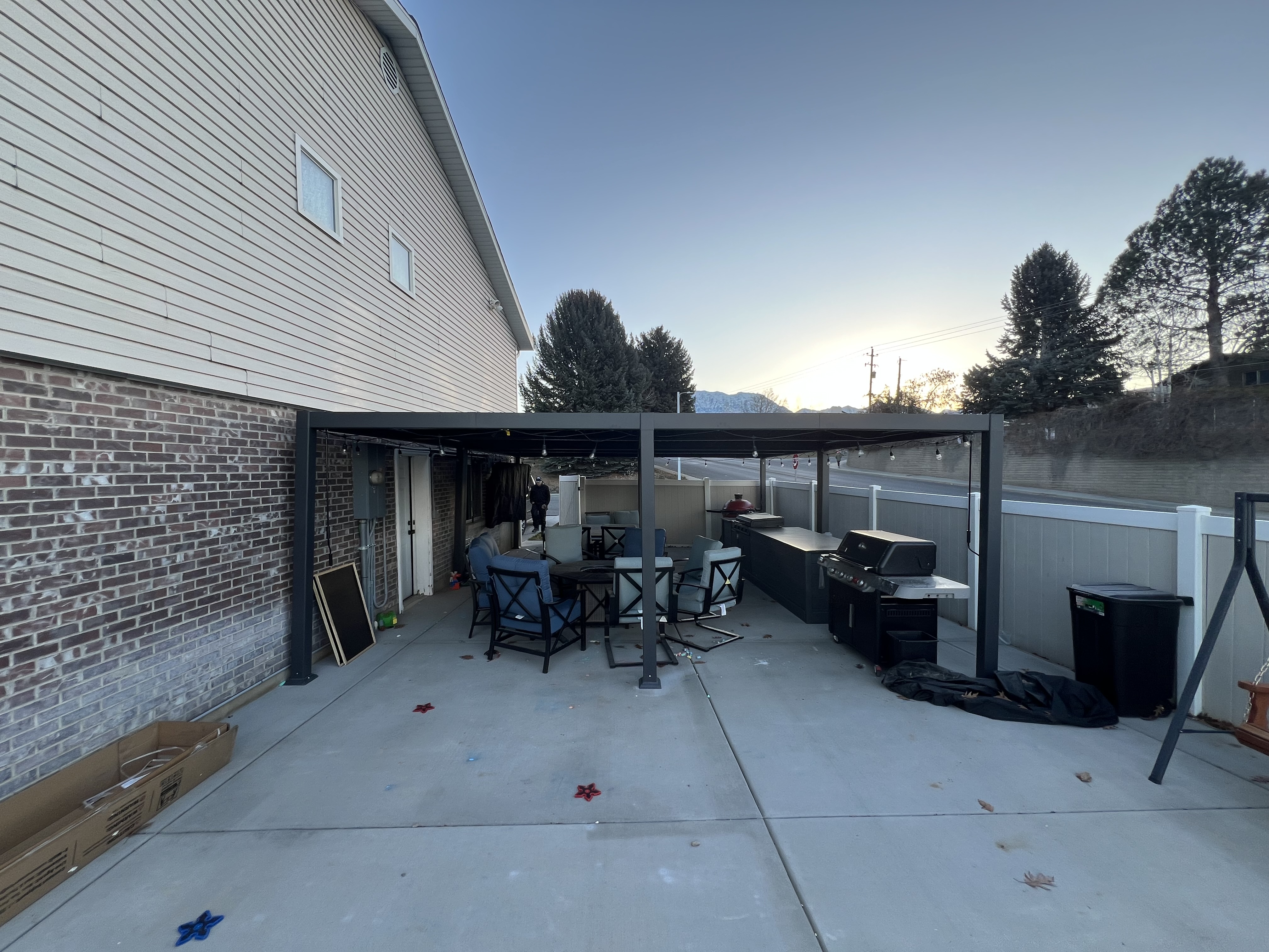 Custom outdoor kitchen with new concrete, a pergola, and a custom kitchen workspace with black granite countertop